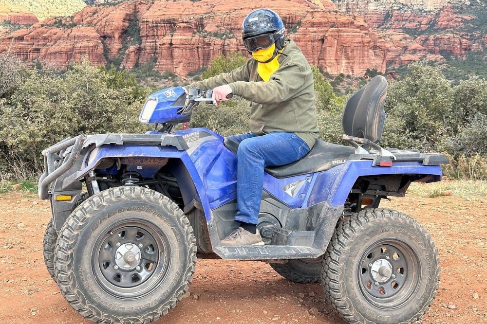 ATV ride gear, featuring a helmet, protective goggles, jacket, and closed toed shoes. Set against a desert landscape background with cacti and rocky terrains, showcasing the adventurous spirit of off-roading in Arizona.